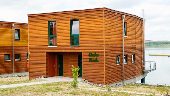 Dies ist ein Bild von den Metallbuchstaben ARCHE NOAH in Aluminium moosgrün an Holz-Ferienhäusern