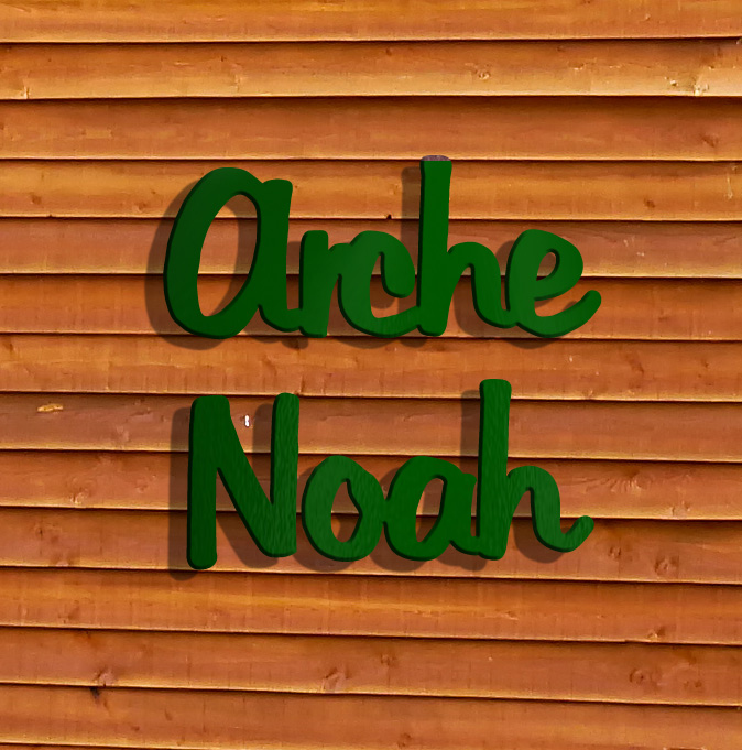 Dies ist ein Bild von den Metallbuchstaben ARCHE NOAH in Aluminium moosgrün an Holz-Ferienhäusern