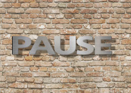 Dies ist ein Bild mit Edelstahlbuchstaben an einer Klinkerwand. Die Einzelbuchstaben zeigen das Wort PAUSE