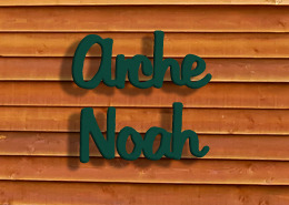Dies ist ein Bild einer Holzwand mit einem Metall Schriftzug Arche Noah als Ferienhaus Namen