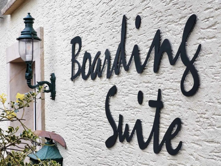 Dieses Bild zeigt den Metall Schriftzug BOARDING SUITE an der Fassade des Markenshop für Hausschilder